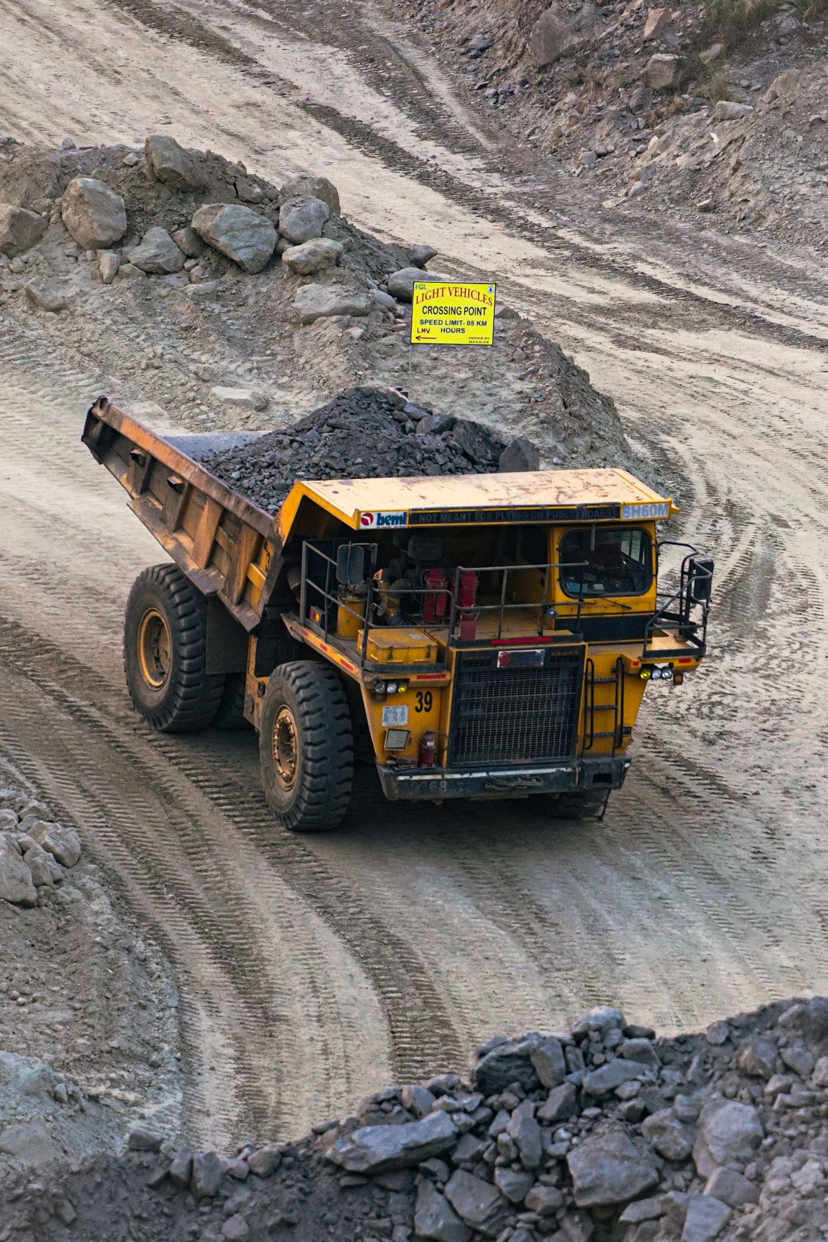 Heavy mining truck transporting minerals in a rocky open-pit quarry in Bahula, West Bengal.